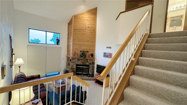 stairway with carpet flooring, wood walls, and a fireplace