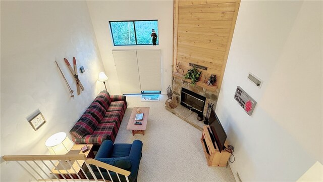 living room featuring light carpet, a fireplace, and a high ceiling