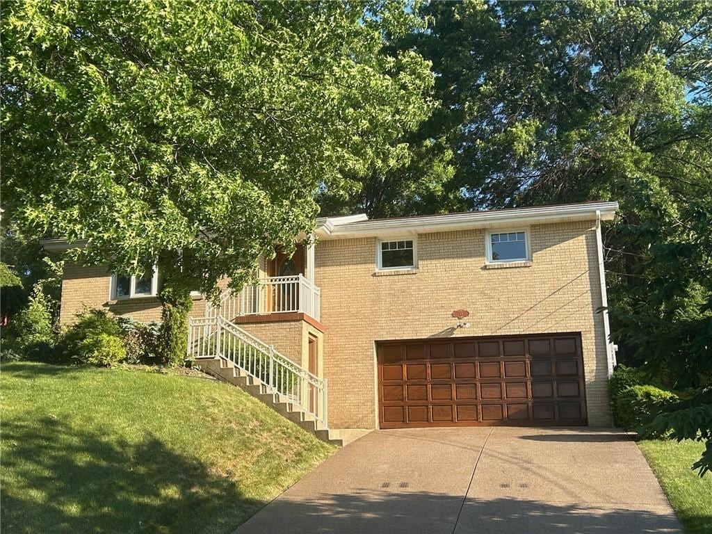 view of front facade with a garage, driveway, brick siding, and a front lawn