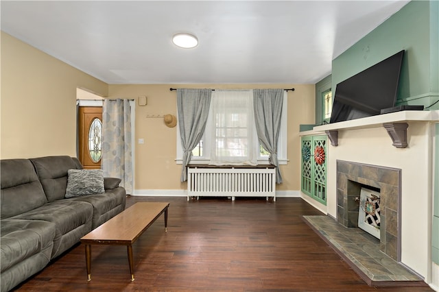 living room featuring a tile fireplace, radiator, and dark wood-type flooring