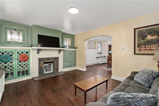 living room featuring a tiled fireplace and dark hardwood / wood-style flooring