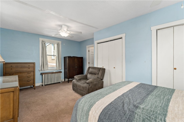 carpeted bedroom with radiator heating unit, multiple closets, and ceiling fan