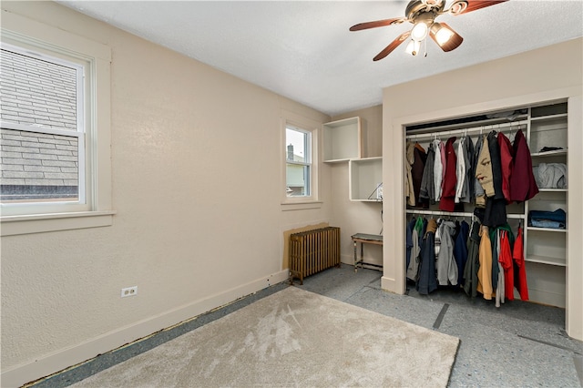 unfurnished bedroom featuring ceiling fan, radiator heating unit, and a closet