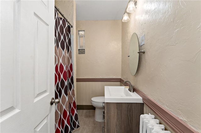 bathroom featuring radiator heating unit, hardwood / wood-style flooring, vanity, and toilet