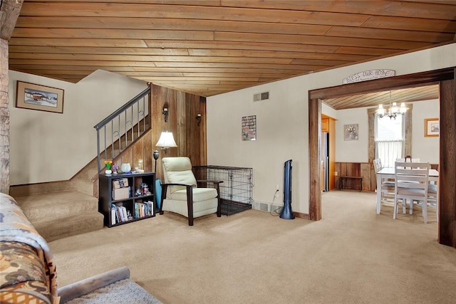 carpeted living room with a notable chandelier, wood ceiling, and wooden walls