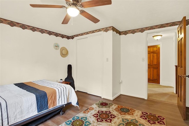 bedroom with ceiling fan, dark wood-type flooring, and a closet