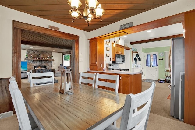 carpeted dining room with a fireplace, wooden ceiling, and a notable chandelier