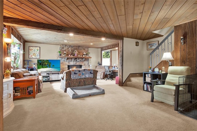 living room featuring beamed ceiling, light carpet, a stone fireplace, and wooden walls