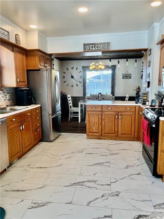 kitchen with stainless steel refrigerator, sink, an inviting chandelier, black range with electric cooktop, and decorative light fixtures