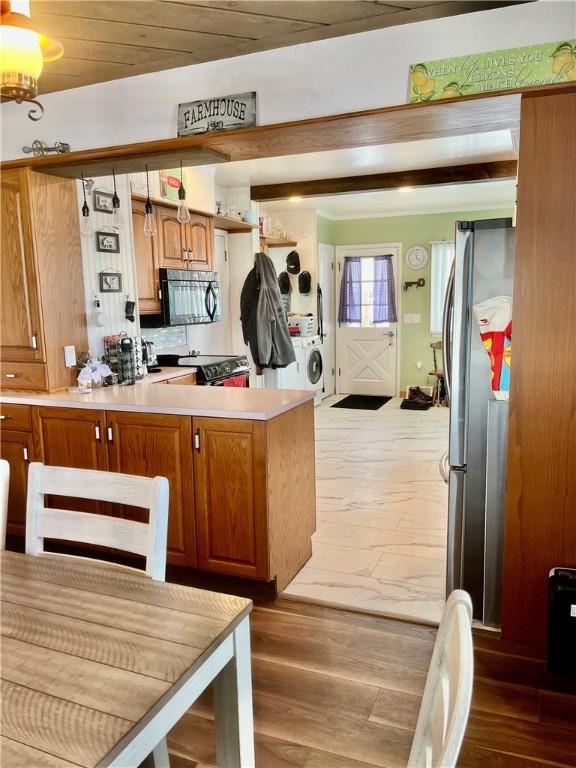 kitchen with dark hardwood / wood-style floors, washer / dryer, kitchen peninsula, and stainless steel refrigerator