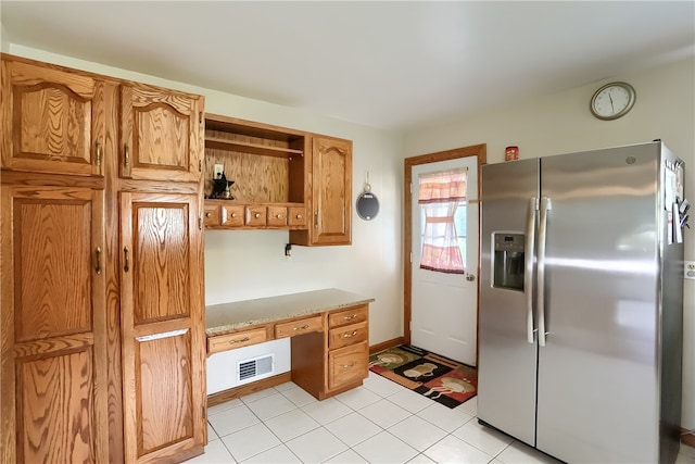 kitchen featuring built in desk, light tile patterned flooring, and stainless steel refrigerator with ice dispenser