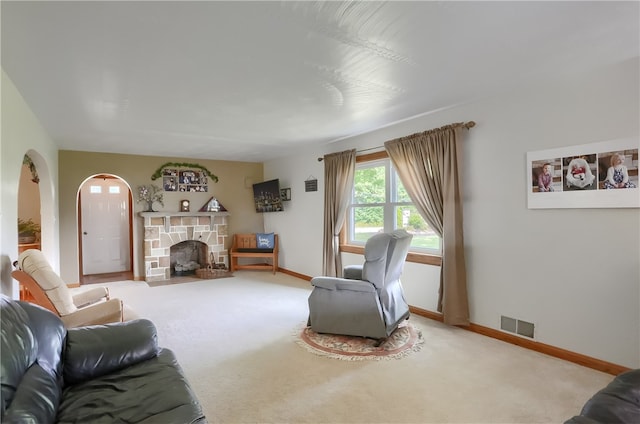 carpeted living room featuring a stone fireplace