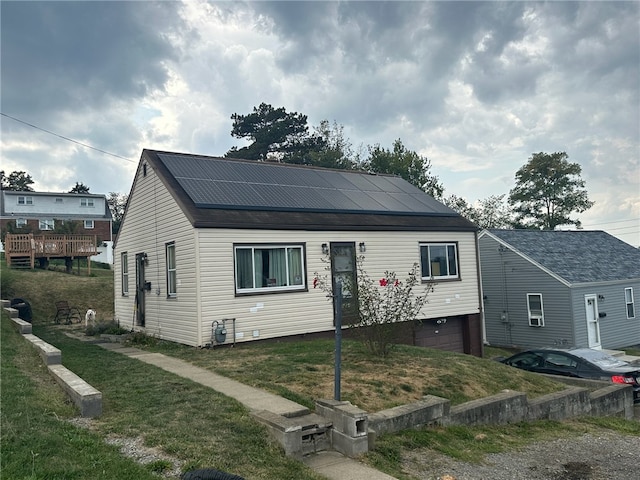 bungalow-style house with a front yard, solar panels, and a garage