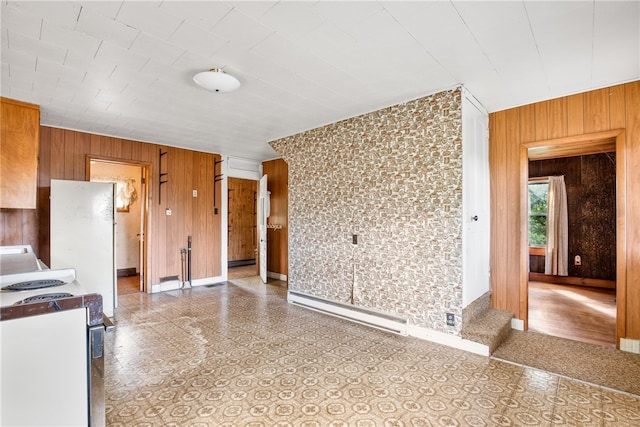 kitchen with wooden walls, electric range, baseboard heating, and light tile patterned flooring