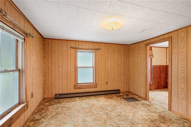 carpeted spare room with wood walls and baseboard heating