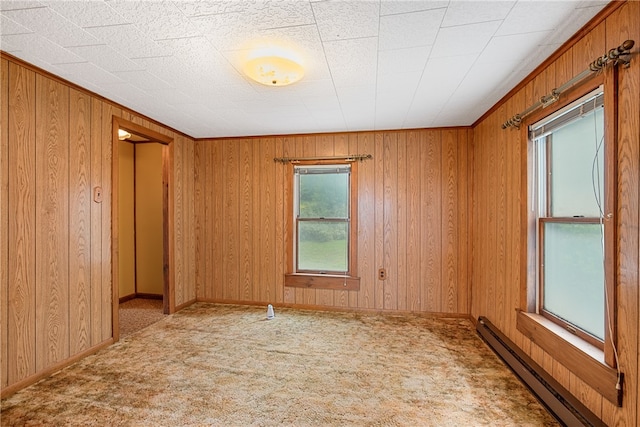 spare room featuring wood walls, baseboard heating, and light carpet