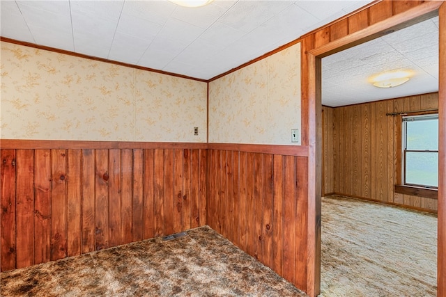 unfurnished room with ornamental molding, carpet, and wood walls