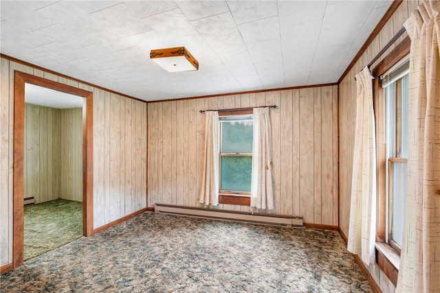 unfurnished room with a baseboard heating unit, crown molding, wood walls, and carpet floors