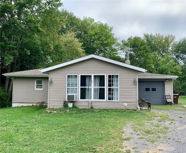 rear view of property featuring a garage and a lawn