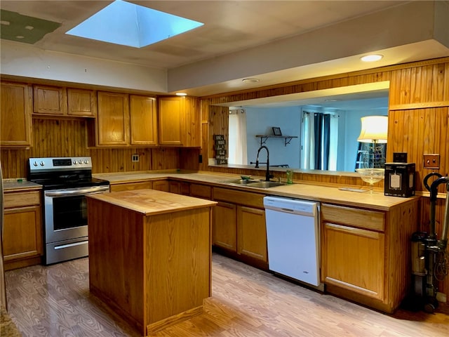 kitchen featuring a skylight, stainless steel electric stove, wood counters, a center island, and white dishwasher