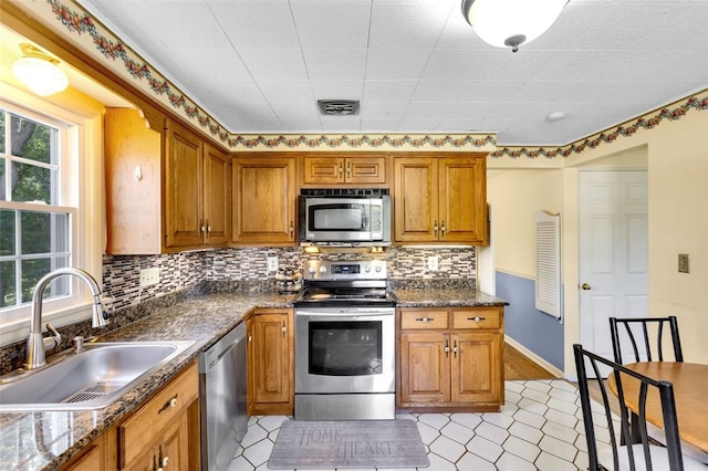 kitchen featuring a wealth of natural light, decorative backsplash, sink, and appliances with stainless steel finishes