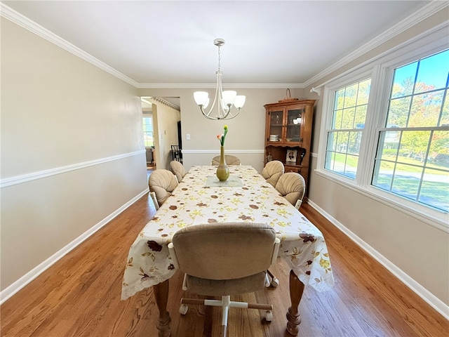 dining room with crown molding, an inviting chandelier, and light wood-type flooring