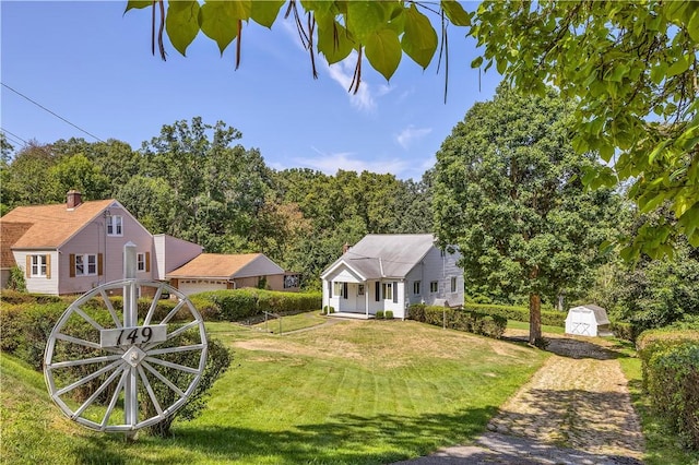 view of front of house with a storage shed, fence, a front lawn, and an outdoor structure