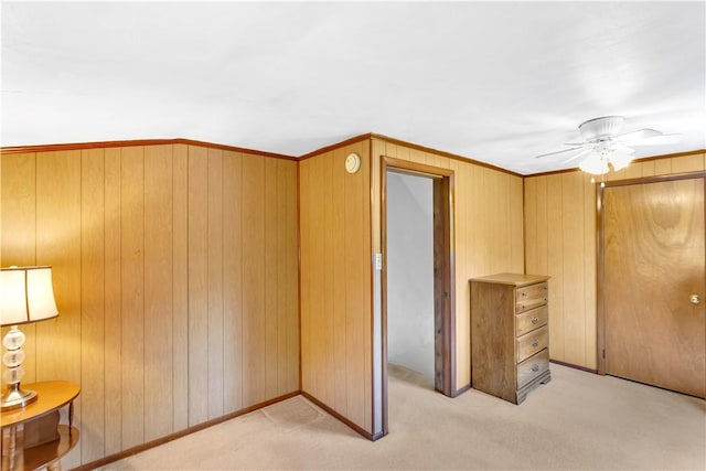 unfurnished bedroom with light carpet, wood walls, and a closet