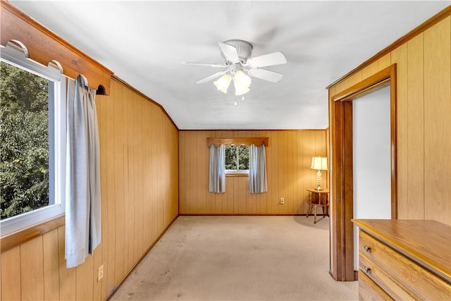 empty room featuring light carpet, wood walls, and ceiling fan