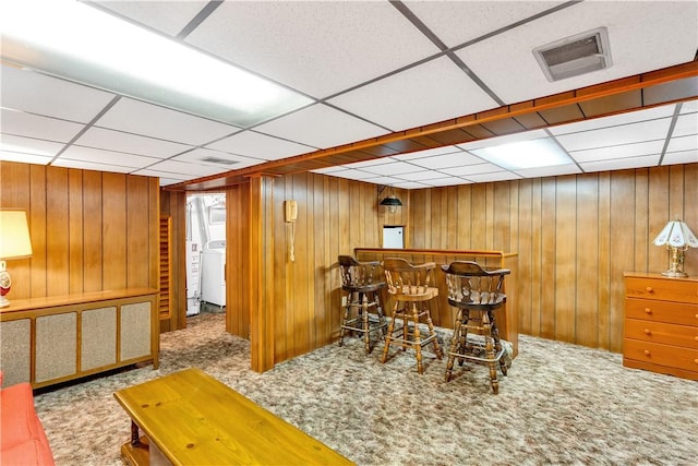 interior space featuring washer / dryer, visible vents, wood walls, and a bar