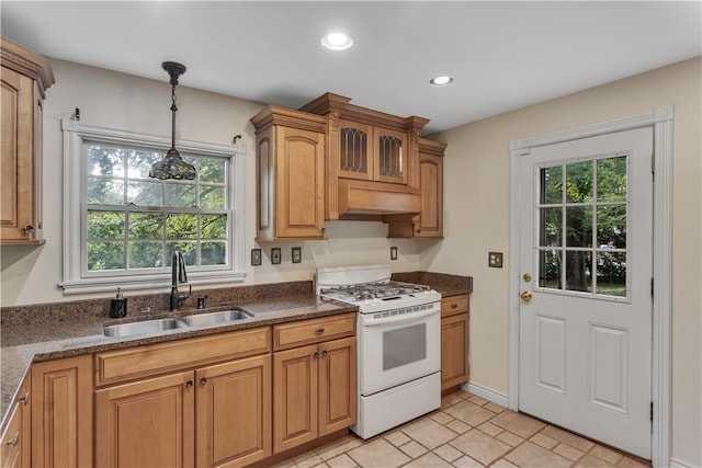 kitchen with light tile patterned floors, white range with gas stovetop, sink, and a healthy amount of sunlight