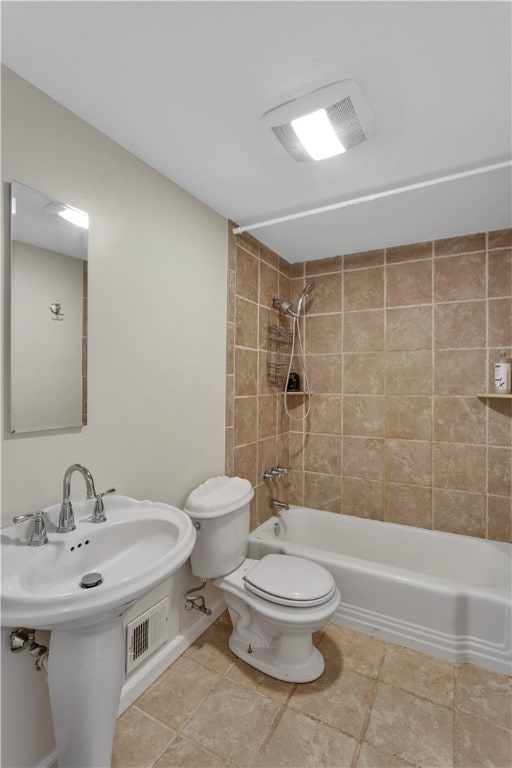 bathroom featuring tiled shower / bath combo, toilet, and tile patterned floors