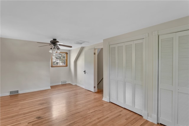 unfurnished bedroom with light wood-type flooring, two closets, and ceiling fan