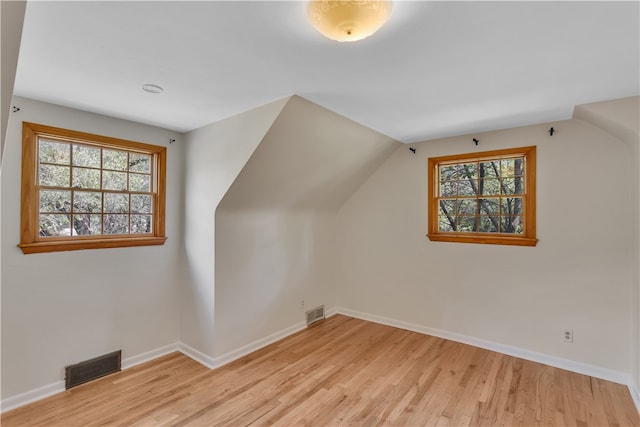 bonus room featuring a wealth of natural light, vaulted ceiling, and light wood-type flooring