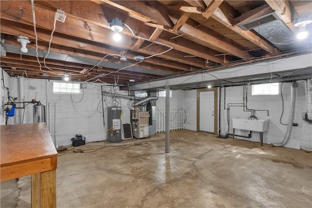 basement featuring gas water heater, sink, heating unit, and a healthy amount of sunlight