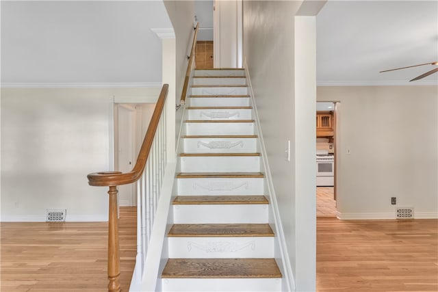 stairway featuring ceiling fan, hardwood / wood-style flooring, and crown molding