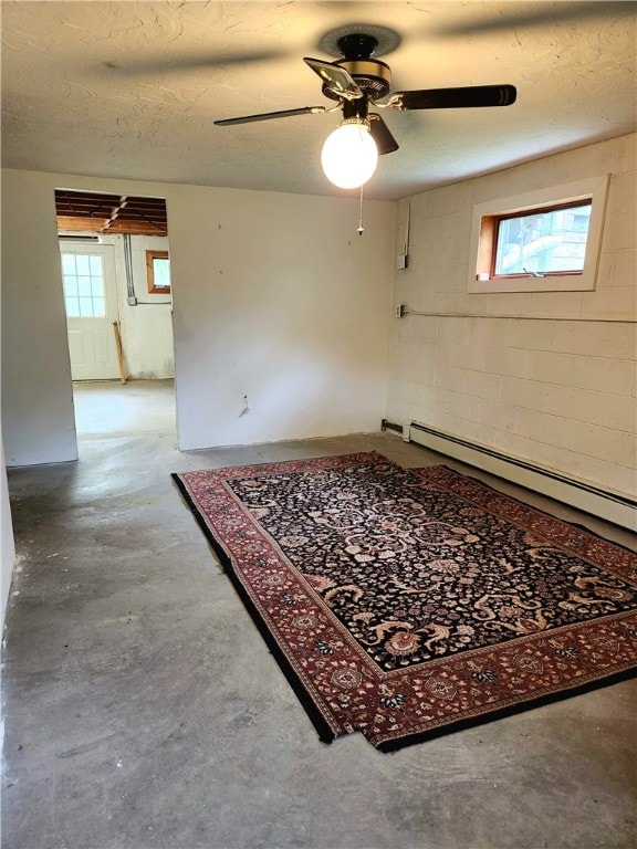 spare room featuring concrete flooring, ceiling fan, baseboard heating, and a textured ceiling