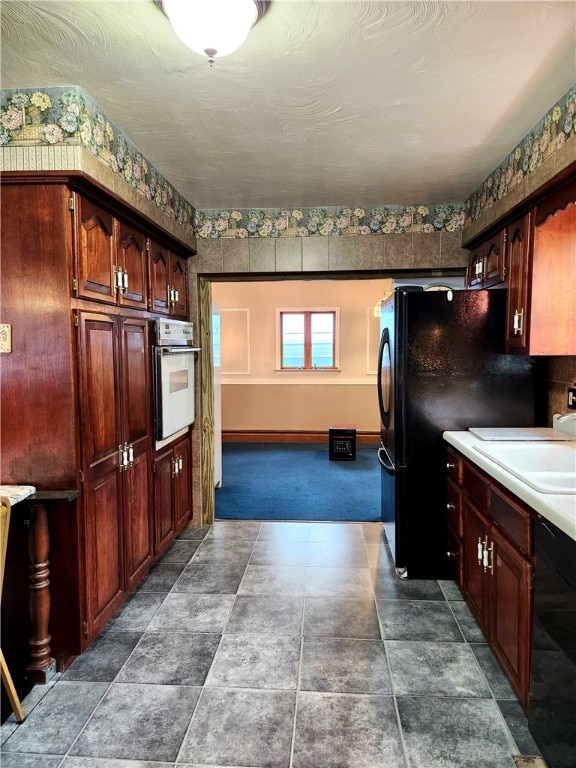 kitchen featuring dark carpet, black appliances, and sink