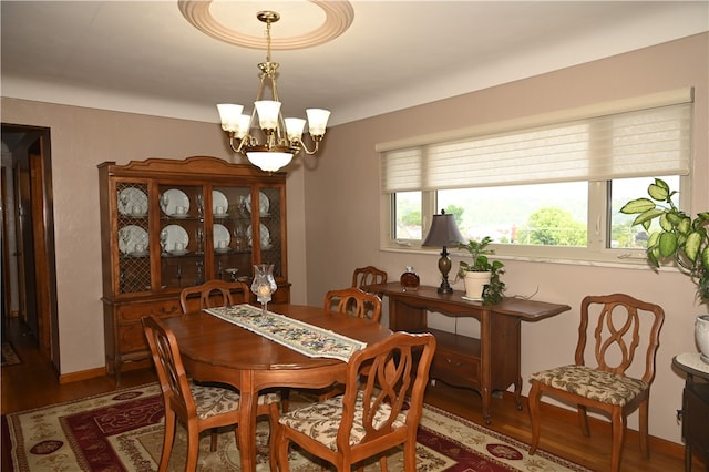 dining area with hardwood / wood-style floors and an inviting chandelier