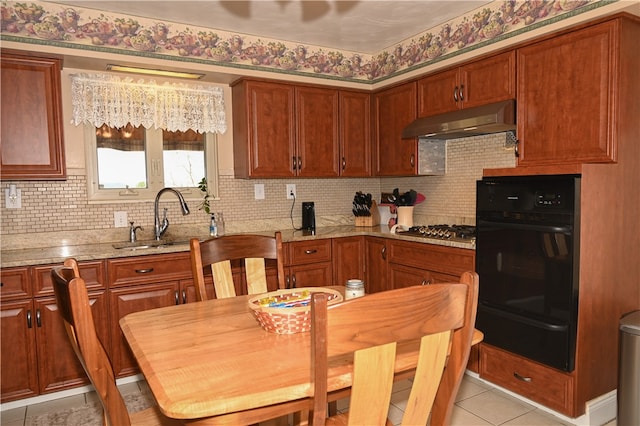 kitchen featuring tasteful backsplash, stainless steel gas stovetop, sink, light stone countertops, and light tile patterned flooring