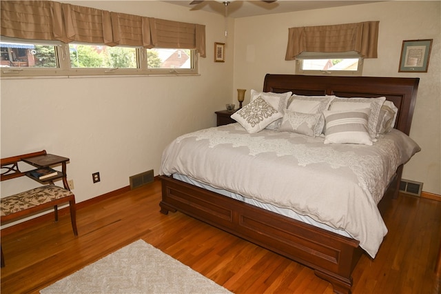 bedroom with ceiling fan, dark hardwood / wood-style floors, and multiple windows