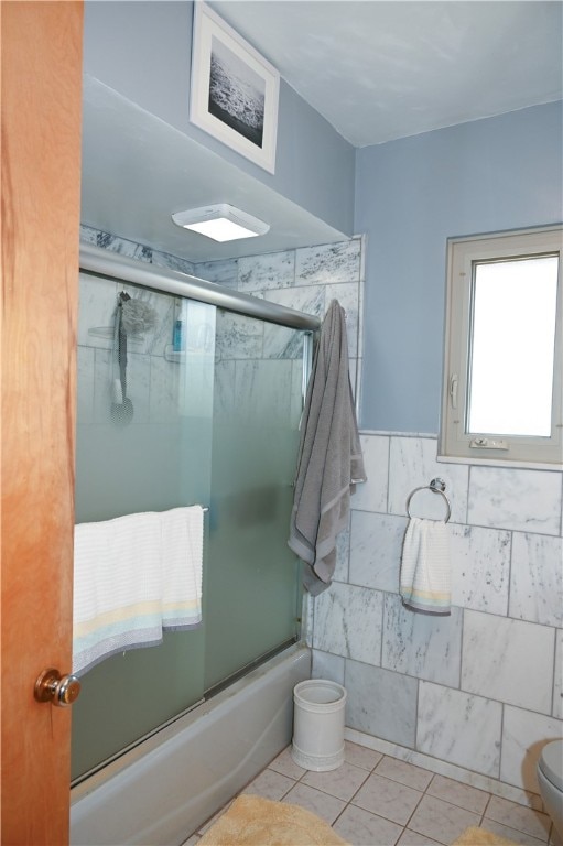 bathroom featuring shower / bath combination with glass door, toilet, tile walls, and tile patterned floors