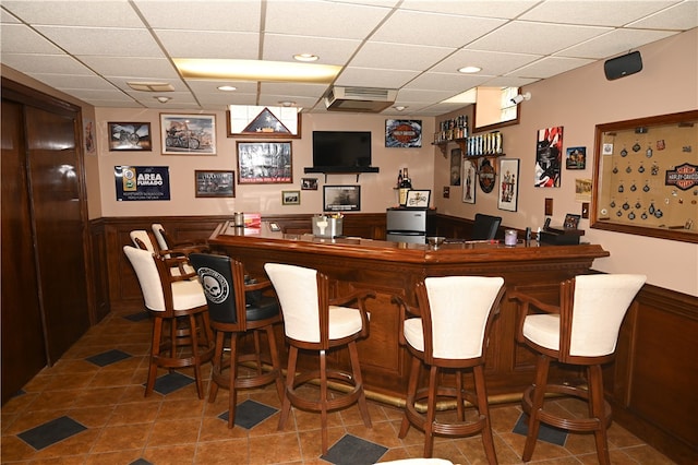 bar featuring a paneled ceiling and tile patterned flooring