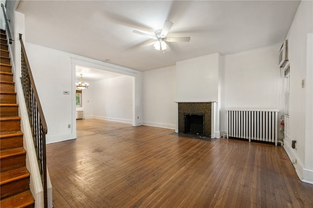 unfurnished living room with radiator, ceiling fan with notable chandelier, and dark hardwood / wood-style floors