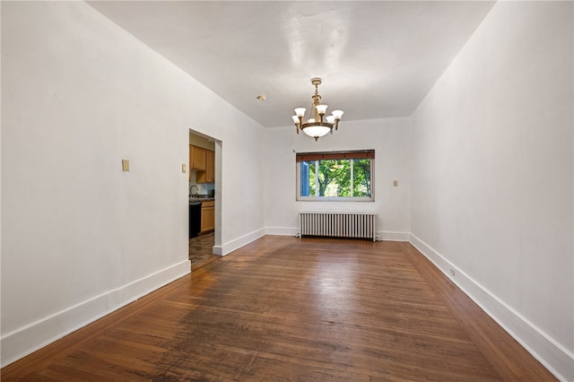 spare room featuring a chandelier, radiator, dark wood finished floors, and baseboards