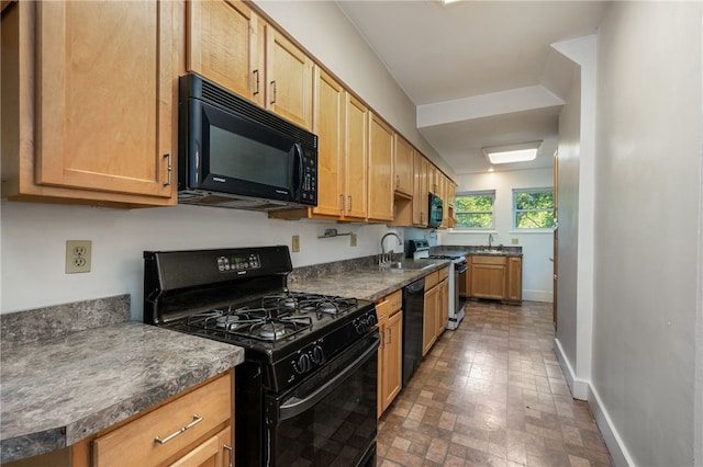 kitchen with dark countertops, baseboards, a sink, and black appliances