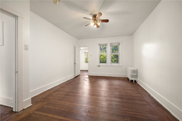 spare room featuring radiator, ceiling fan, baseboards, and wood finished floors