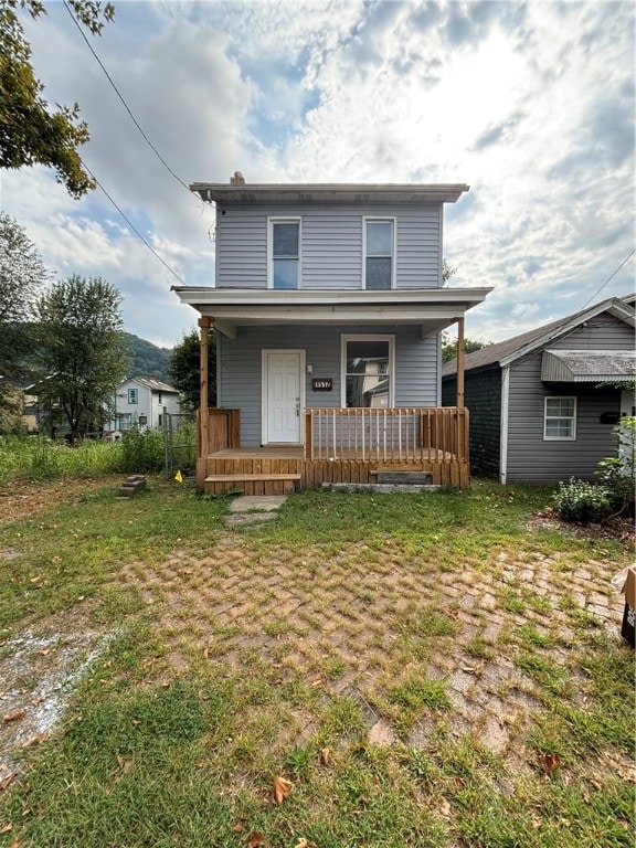 rear view of house featuring a lawn and covered porch