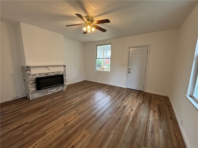 unfurnished living room featuring a fireplace, dark hardwood / wood-style flooring, and ceiling fan