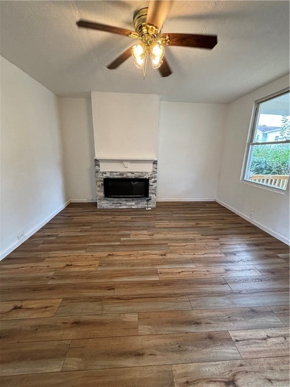 unfurnished living room with a fireplace, wood-type flooring, and ceiling fan